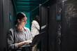 © Seventyfour - Waist up portrait of female data engineer using laptop in server room while setting up supercomputer network, copy space