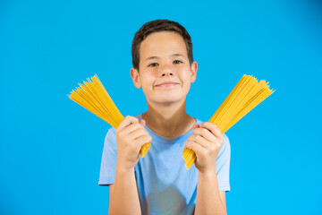 Cute smiling boy holding traditional Italian spaghetti in his hands.