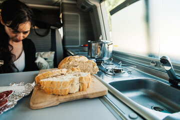 A young woman having breakfast in her caravan observing a good view of the beach