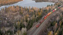 A Long And Colorful Freight Train Pulling A Large Number Of Shipping And Cargo Containers Through The Canadian Shield.  Boreal Forest.  Drone. 4k.