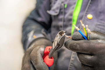 electrician hands hold wire cutters and close-up of wires. the idea of repairing and connecting elec