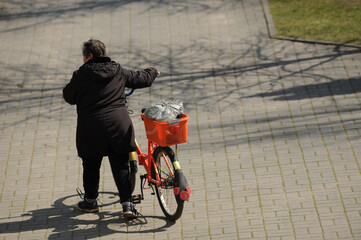 Wall Mural - old woman walking with her bike