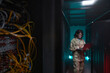 © Seventyfour - Portrait of young African-American woman wearing military uniform using laptop while standing in server room, copy space