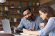 © insta_photos - Two multiethnic professionals colleagues working together with laptop and papers in office. Indian male mentor and latin female young professional sitting in creative office space.