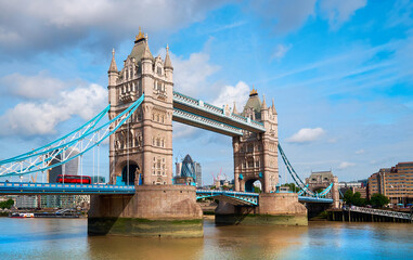Wall Mural - Tower Bridge on a bright sunny day with blue sky and clouds. Calm river water with reflections. Dramatic sky. London, England, UK.