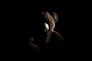 Teddy bear in the darkness being lit only by one light. Silhouette.