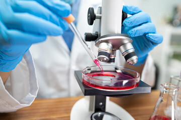 Asian scientist biochemist or microbiologist working research with a microscope in laboratory. For protect outbreak Coronavirus Covid19, bacteria and germs.