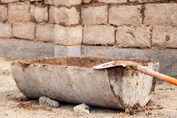 Half of metal barrel with cement, dirty old shovel in concrete