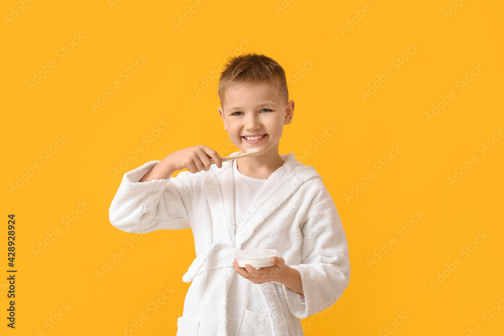 Little boy brushing teeth on color background