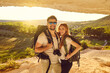 © Studio Romantic - Happy young couple of hikers standing in mountains cave at sunset. Tourists mountaineering on summer vacation