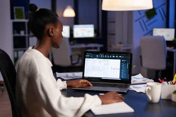 Poster - African engineer writing builder strategy on paperwork while analyzing architectural construction plan on laptop computer. Professional architect working at creative engineering architecture