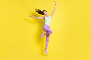 Wall Mural - photo of charming positive lady raise hands jump wear green top pants footwear isolated yellow color