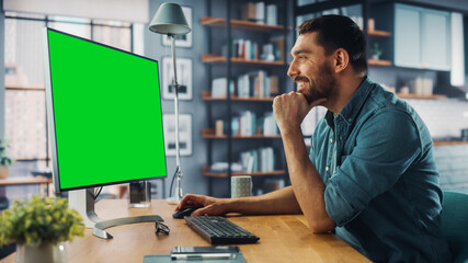 Wall Mural - Handsome Caucasian Specialist Working on Desktop Computer with Green Screen Mock Up Display at Home Living Room. Freelance Man Chatting to Clients Over the Internet on Social Networks.