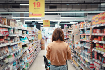 Fototapete - Female customer shopping at supermarket with trolley.