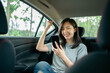 © Worranan - Asian woman sitting in a car is delighted after seeing a message on her cell phone.