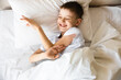 © Marina Andreichenko - Cute little caucasian boy wake up in his comfortable bed in the morning under sun light. Stretches and yawns. Good morning