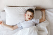 © Marina Andreichenko - Cute little caucasian boy wake up in his comfortable bed in the morning under sun light. Stretches and yawns. Good morning