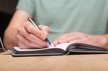 Poster - Male hands taking notes, writing plans in notebook or planner. Planning in schedule diary, close up.