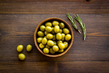 Green olives in wooden bowl. Overhead view