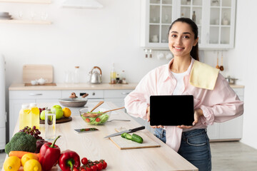 Poster - Woman showing tablet with empty screen for mockup in kitchen