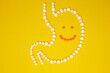 © Aleksandr - A cheerful face in a stomach of pills on a yellow background. Healthy lifestyle, good digestion