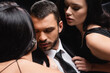 © LIGHTFIELD STUDIOS - sexy, brunette women seducing young businessman isolated on black.