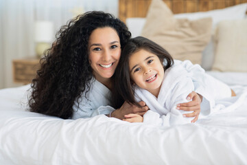 Wall Mural - Adorable young mother and cute daughter bonding on bed