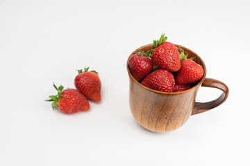 Strawberries in a wooden mug, on a light background. Summer concept, harvest, there is a place for text