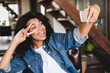 © InsideCreativeHouse - Happy afro young woman taking selfie on her phone in the living room. African businesswoman in home office. Beautiful young women making selfie photo in the home office.