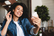 © InsideCreativeHouse - Pretty african-american girl having video call on her phone at home. African woman hold mobile phone look at device screen smiles enjoy online chat with boyfriend, e-dating active user