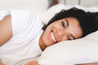 © InsideCreativeHouse - Happy smiling young african woman lying in her white bed in the morning. Young African American woman waking up at home.