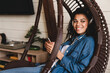 © InsideCreativeHouse - Portrait of an african-american young woman listening to the music in rocking chair. Happy relaxed african woman wear wireless headphones listening to lounge music relaxing after work.