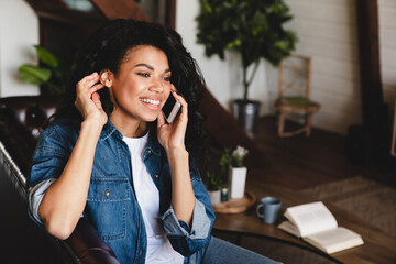 african-american young woman talking on phone in her cosy house. businesswoman working from home off