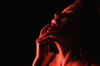 Leinwandbild Motiv red lighting on sexy woman touching lips isolated on black.