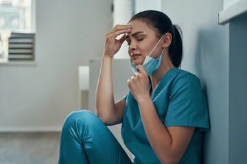 Stressed young female nurse in protective face 