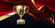 Golden champion cup with wavy red fabric sheets on black background