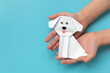 © thayra83 - Child hands holding white paper dog on blue background.