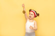 Sport success and win concept - smiling and happy athlete champion child girl celebrates first place victory gold medal award. Sport kid posing over yellow studio background. Banner, mockup,copy space