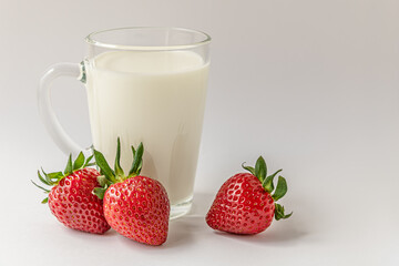 Wall Mural - glass mug of milk and sweet fragrant strawberries on a white surface