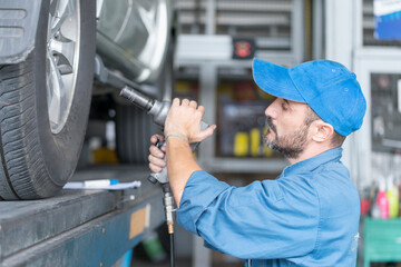 A car mechanic repairing the brakes. Car brake repairing in garage. Car wheel brake disc and shoes of lifted automobile at repair service station.