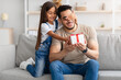 © Prostock-studio - Little girl celebrating father's day, greeting excited dad with box
