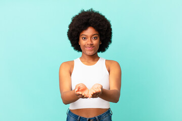 Wall Mural - afro black woman smiling happily with friendly, confident, positive look, offering and showing an object or concept