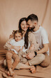 © Ananass - A young sincere family where a stylish bearded father and a cute wife hold their cute children in their arms. Family photo shoot in the studio