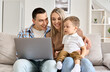 © insta_photos - Happy family mother, father and cute child son having fun using laptop at home. Cute toddler kid boy learning computer doing ecommerce online shopping on technology device sitting with parents on sofa