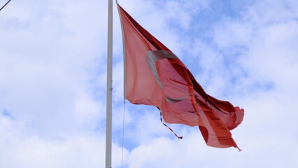 Huge turkish flag with overcast cloudy sky background. Flag is teared