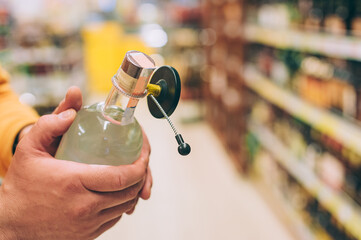 Wall Mural - A male shopper in a supermarket holds a bottle of vodka in his hands.