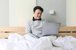 © Reezky - Happy Asian man is working with his laptop on his bed. Concept of freelancer successful lifestyle.