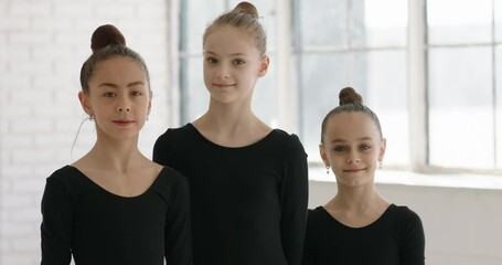 Portrait of three teen girls wearing leotards during dance or gymnastics class looking at camera and positively smiling 4k footage