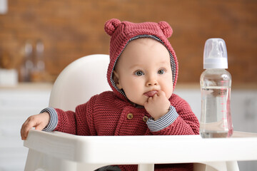 cute little baby with bottle of water in kitchen