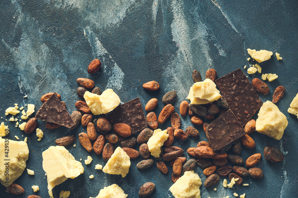 Cocoa butter, chocolate and beans on color background